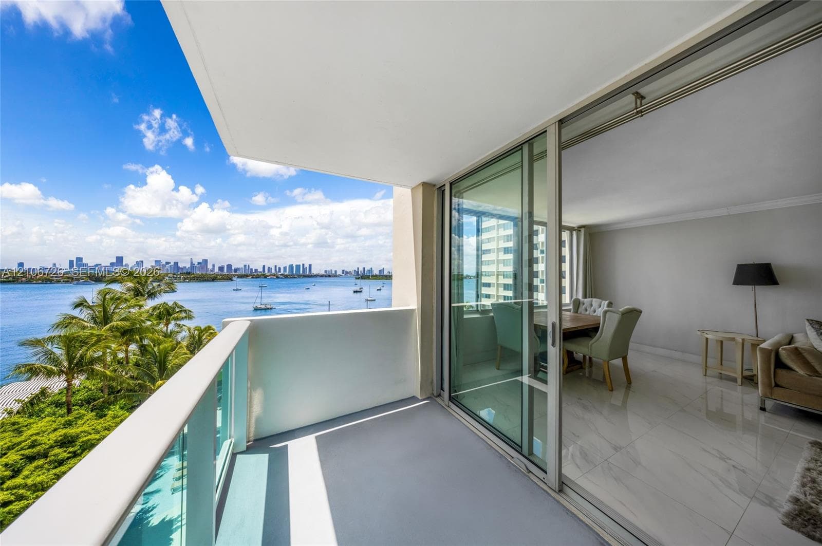 Private balcony featuring a partial glass-panel railing, floor-to-ceiling sliding glass doors, and polished stone-finish flooring