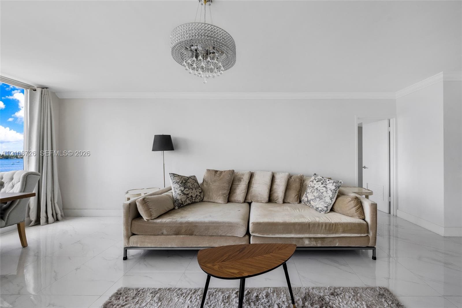 Polished stone flooring, crystal-accented chandelier, and expansive glass paneled window