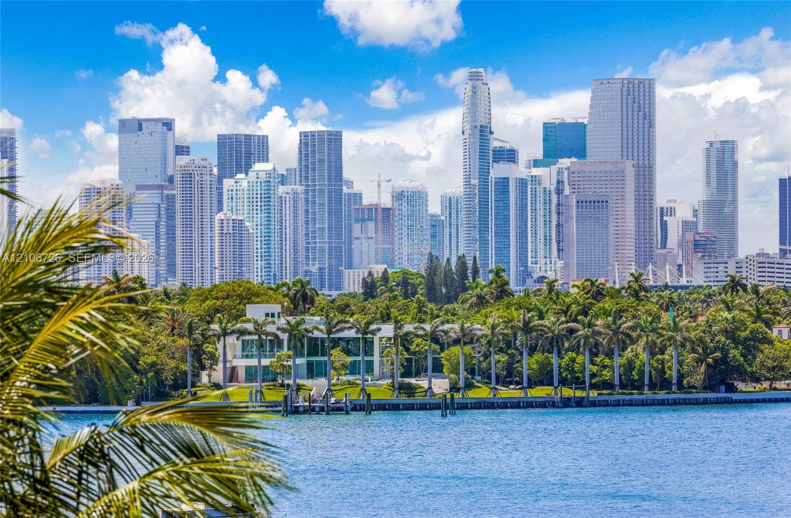 Waterfront estate featuring floor-to-ceiling glass windows, a private dock, and mature perimeter landscaping