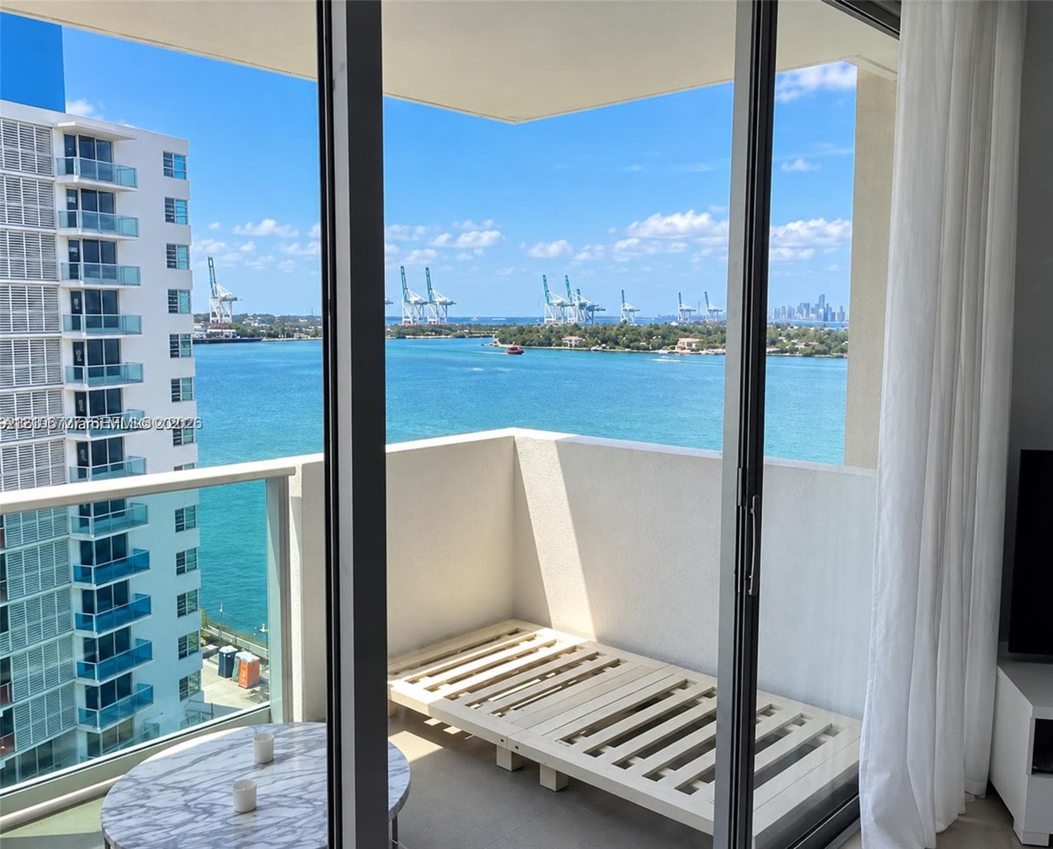 Private balcony featuring floor-to-ceiling glass sliding doors, a glass paneled railing, and water frontage