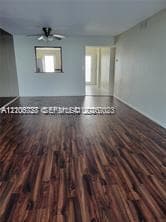 Open floor plan featuring wood-finish flooring, a ceiling fan with integrated lighting, and a pass-through wall opening