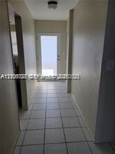 Entryway featuring large-format ceramic tile flooring, neutral wall finishes, and a single-lite glass entry door with a flush-mount ceiling fixture