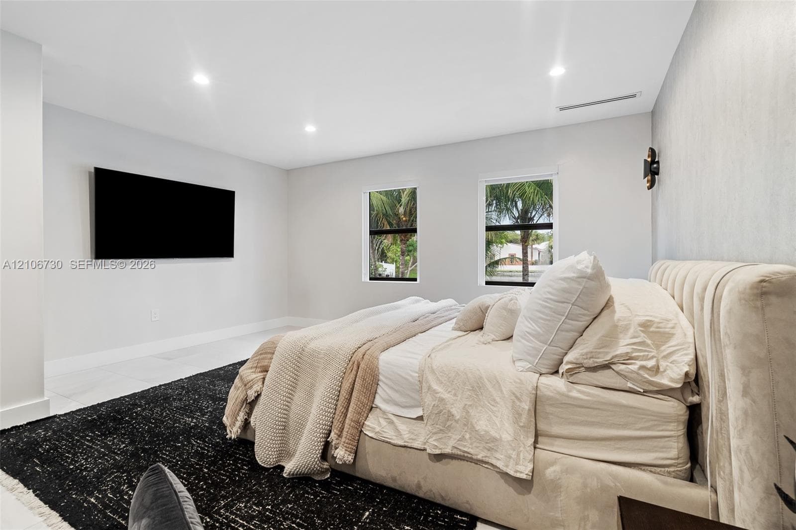 Neutral-toned interior featuring recessed lighting, large-format tile flooring, and dual windows with outdoor greenery