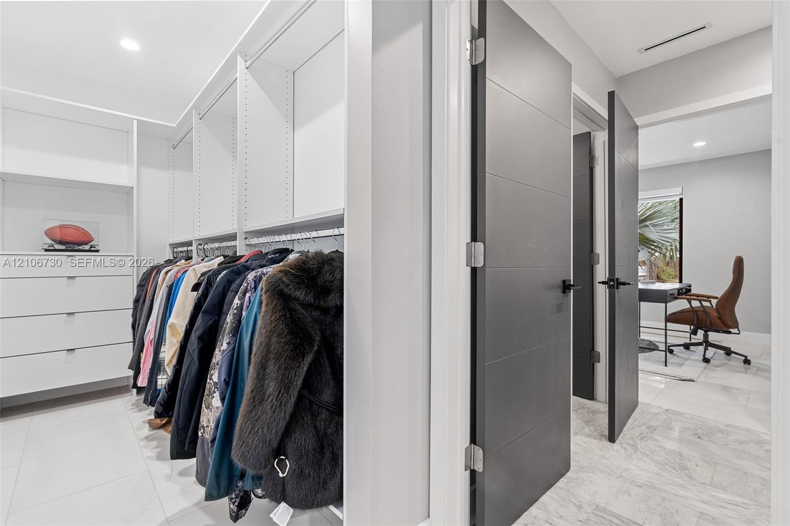 Custom walk-in closet featuring white built-in shelving, integrated storage drawers, and contemporary charcoal-toned interior doors with matte black hardware