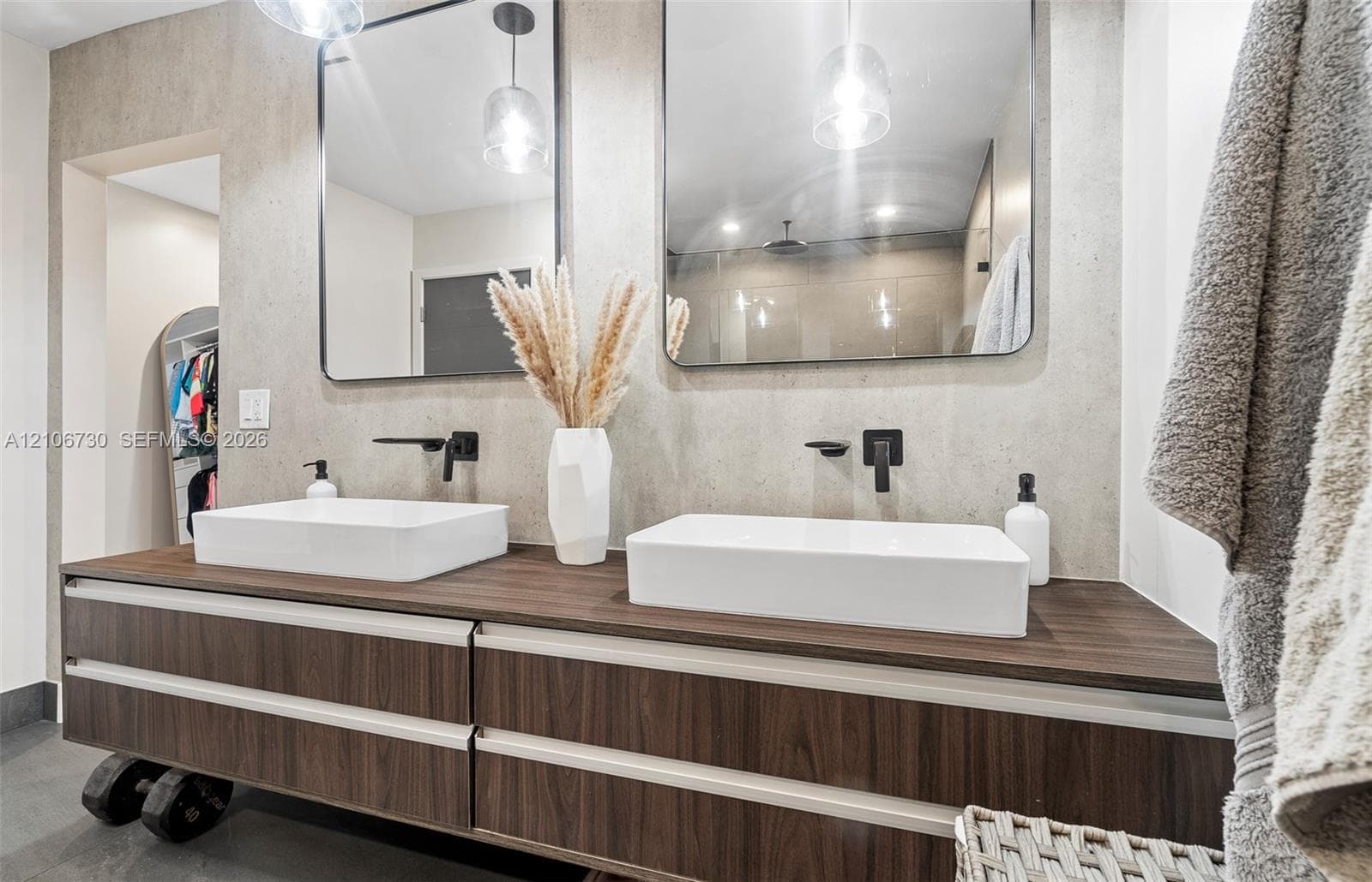 Floating wood-finish vanity with dual rectangular vessel sinks, quartz-finish countertop, matte black wall-mounted faucets, and two rectangular mirrors with integrated pendant lighting