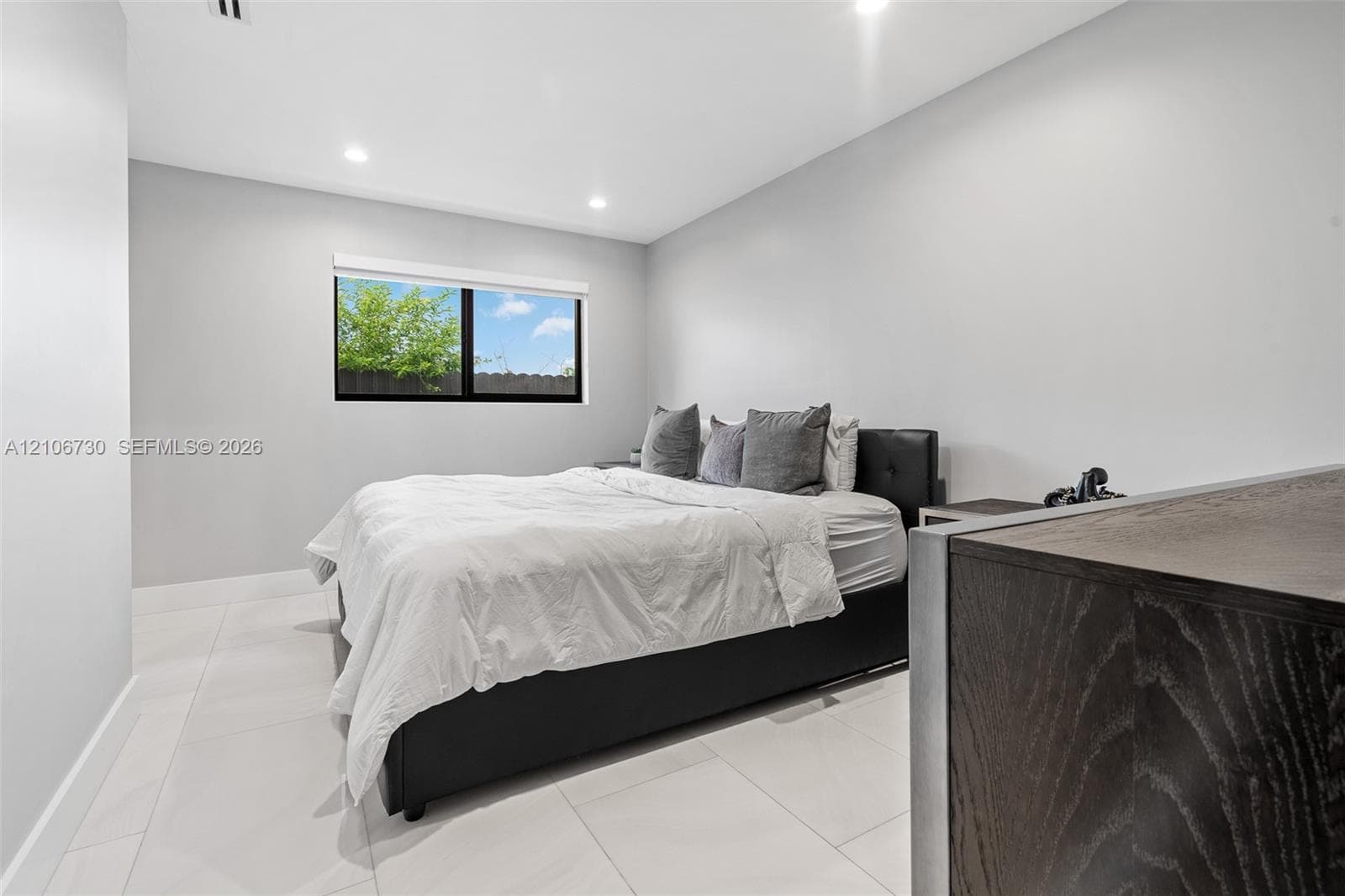 Neutral-toned interior featuring large-format tile flooring, recessed lighting, and a window with a black frame