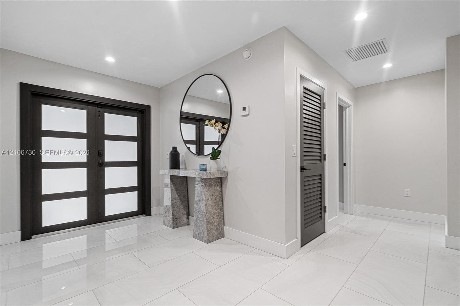 Foyer featuring double-entry doors with frosted glass panels, polished tile flooring, recessed lighting, and a louvered door