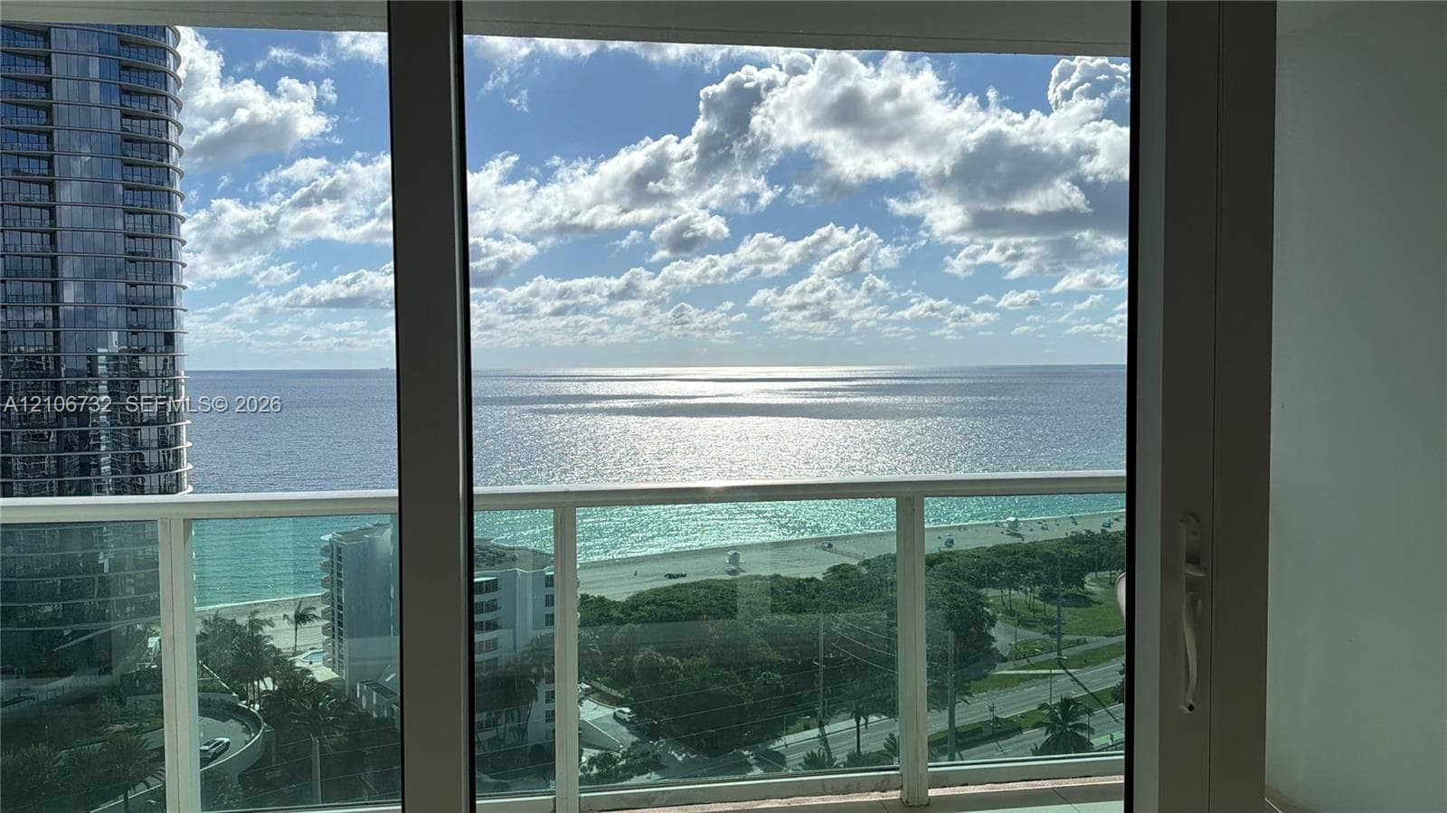 Floor-to-ceiling glass paneling and glass-railed balcony overlooking the ocean coastline