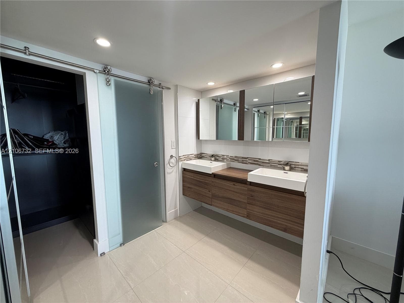 Floating dual vanity with wood-finish cabinetry, rectangular vessel sinks, recessed medicine cabinets, and frosted sliding glass door