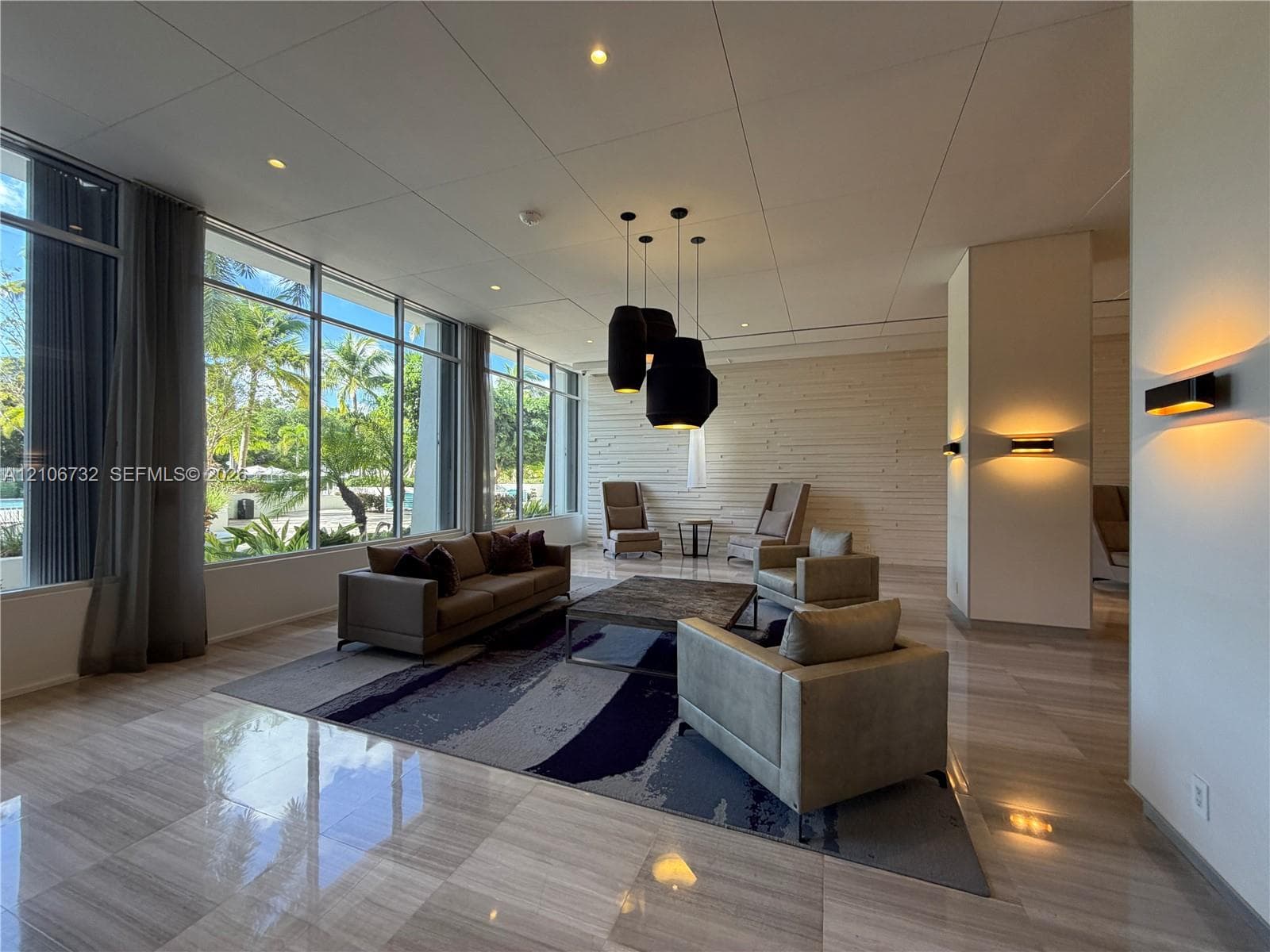 Floor-to-ceiling windows, polished stone flooring, textured accent wall, integrated recessed lighting, and contemporary pendant fixtures