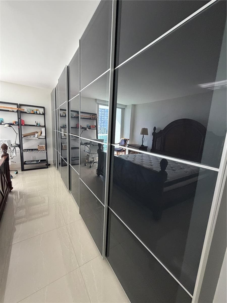 Floor-to-ceiling custom cabinetry with high-gloss charcoal panels and brushed metal framing, complemented by light-toned, large-format tile flooring