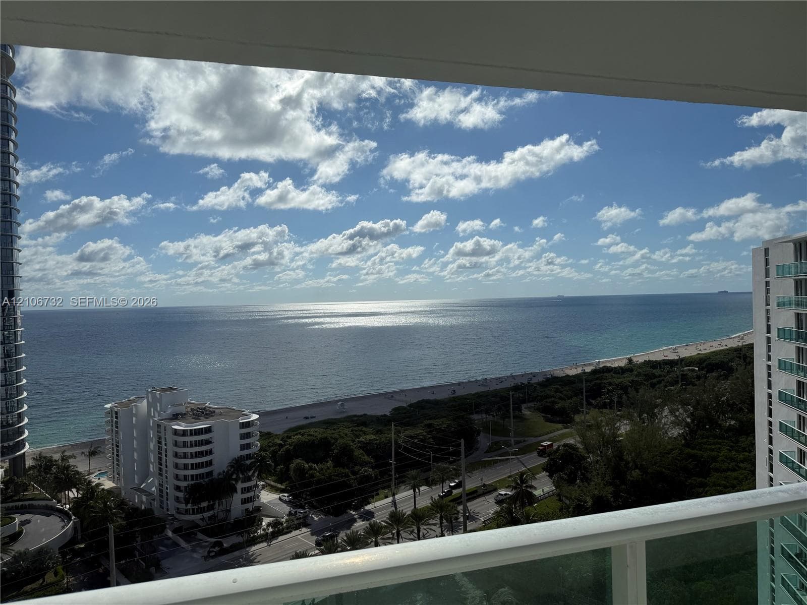 Elevated balcony featuring a glass panel railing and panoramic ocean scenery