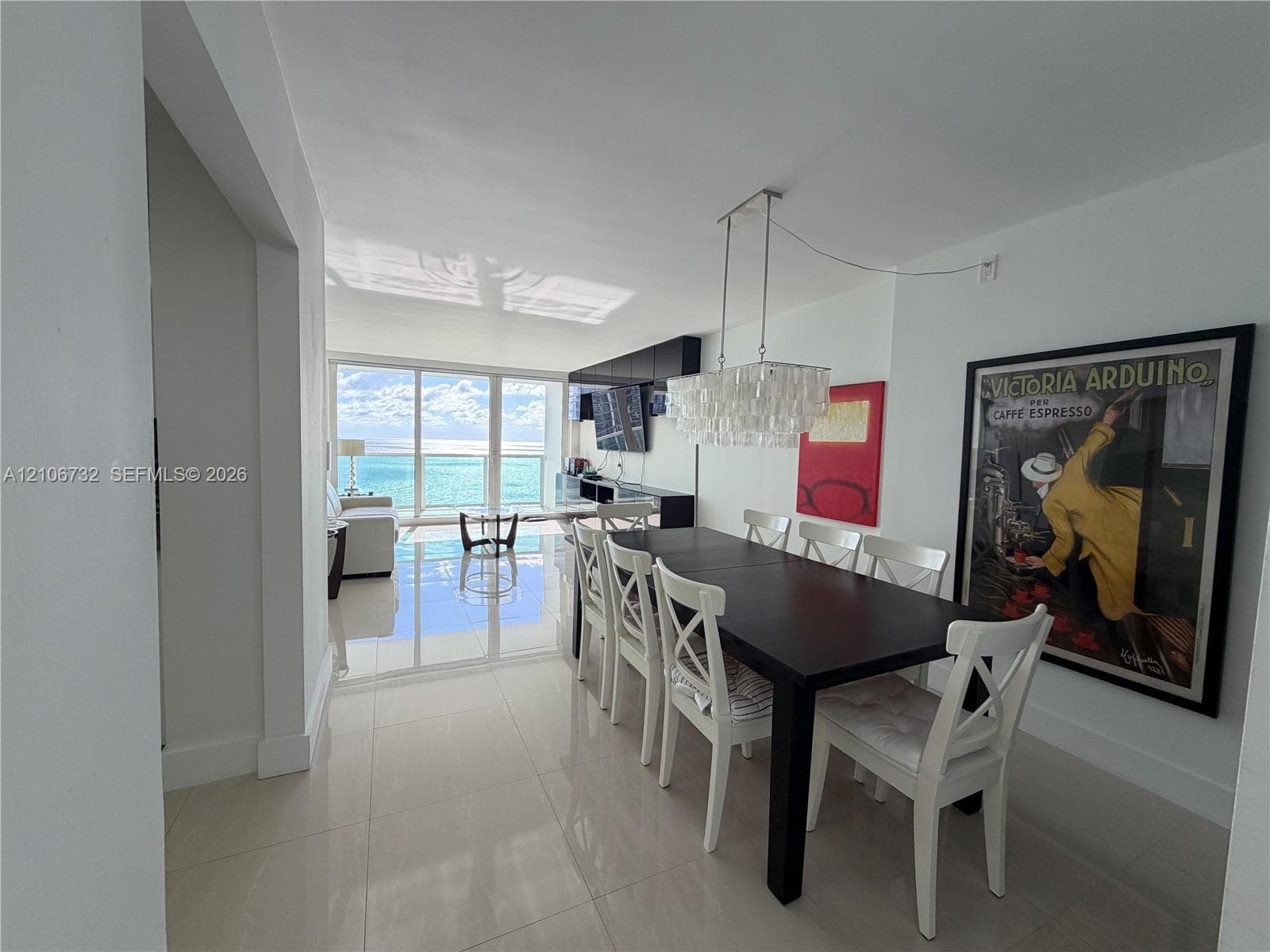 Polished tile flooring, floor-to-ceiling glass wall, built-in dark cabinetry, and decorative tiered glass chandelier