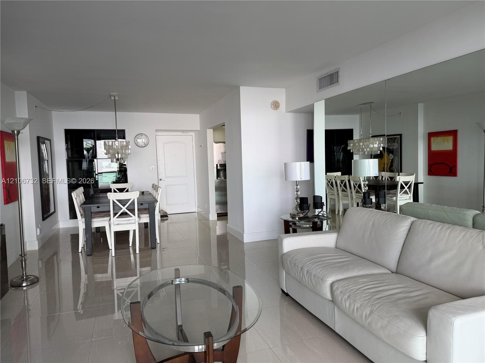 Open-concept interior featuring large-format tile flooring, full-wall mirrors, and a tiered crystal chandelier