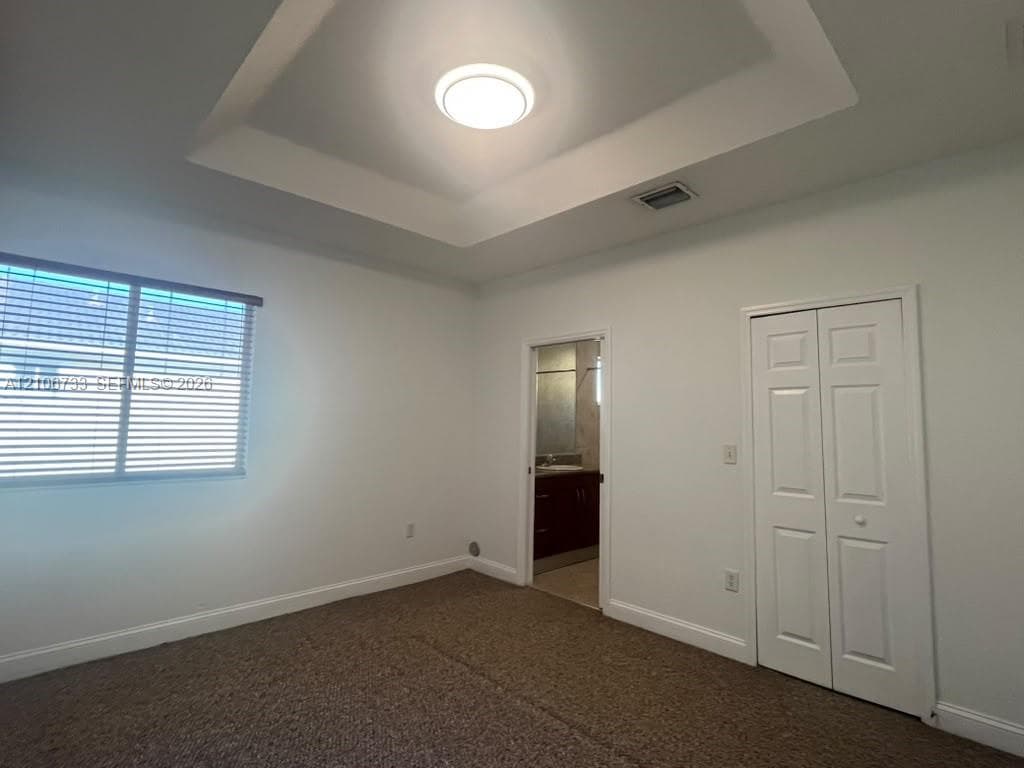 Room featuring a tray ceiling, recessed lighting, wall-to-wall carpeting, and a bifold closet door