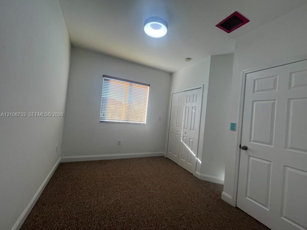 Room featuring neutral wall tones, carpeted flooring, a flush-mount circular light fixture, and double-panel closet doors