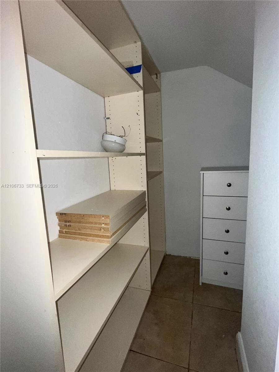 Built-in floor-to-ceiling white shelving and square tile flooring