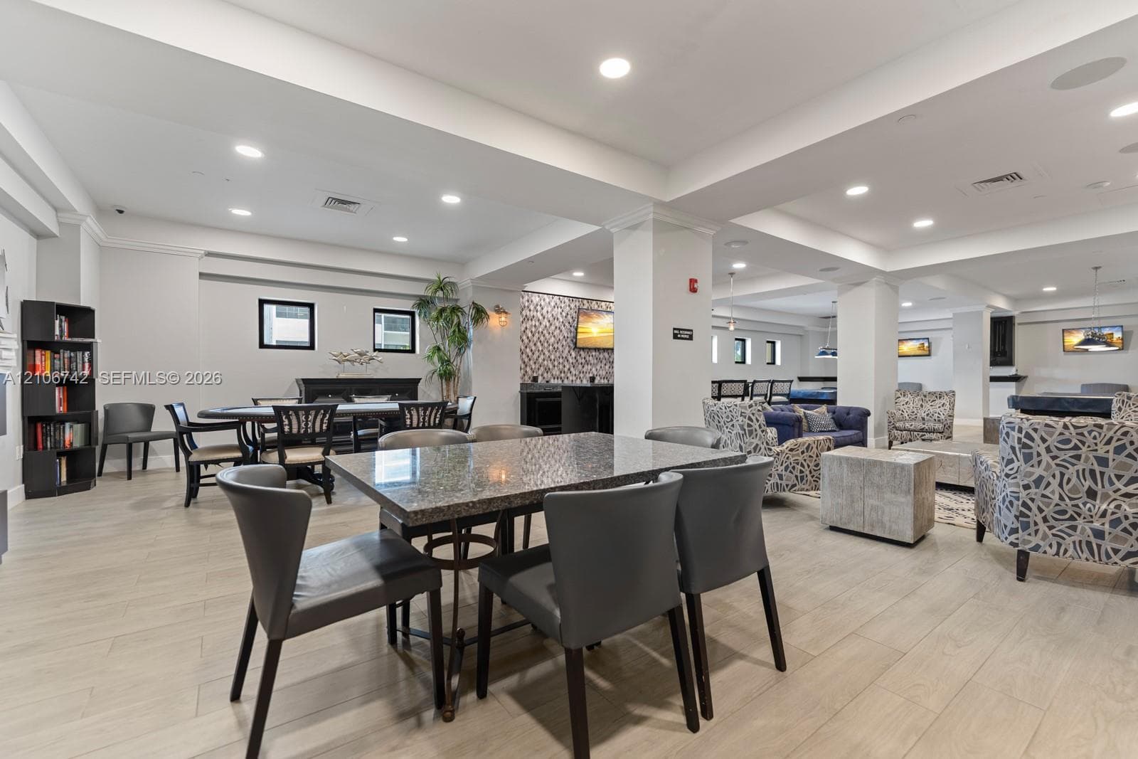 Open-concept interior featuring light wood-finish flooring, recessed lighting, and textured accent wall paneling