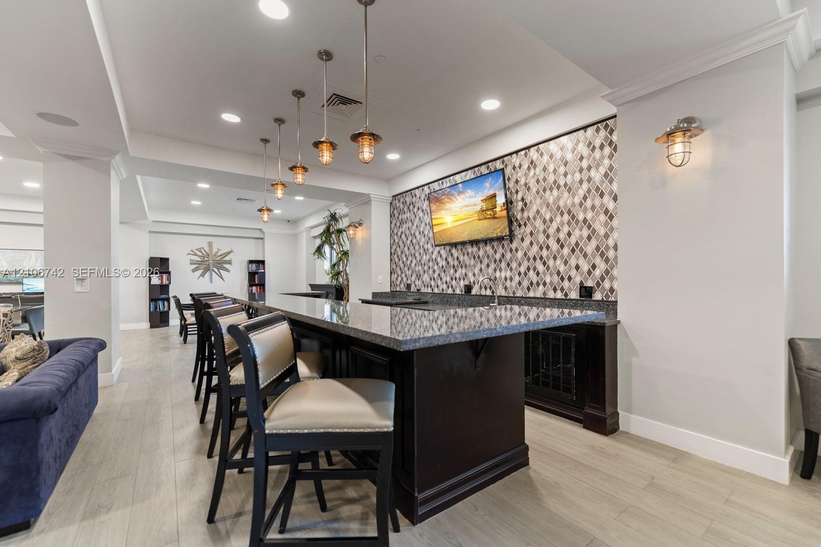 Built-in wet bar featuring stone-finish countertops, geometric tile backsplash, recessed lighting, and pendant fixtures