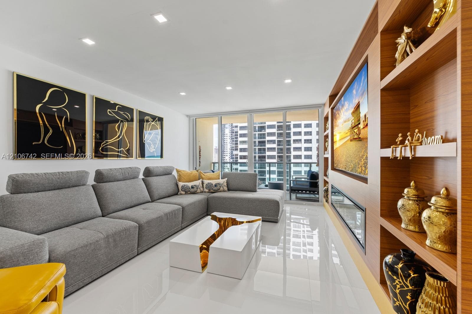 Built-in wood-finish wall shelving, integrated fireplace, floor-to-ceiling glass sliding doors, recessed lighting, and large-format tile flooring