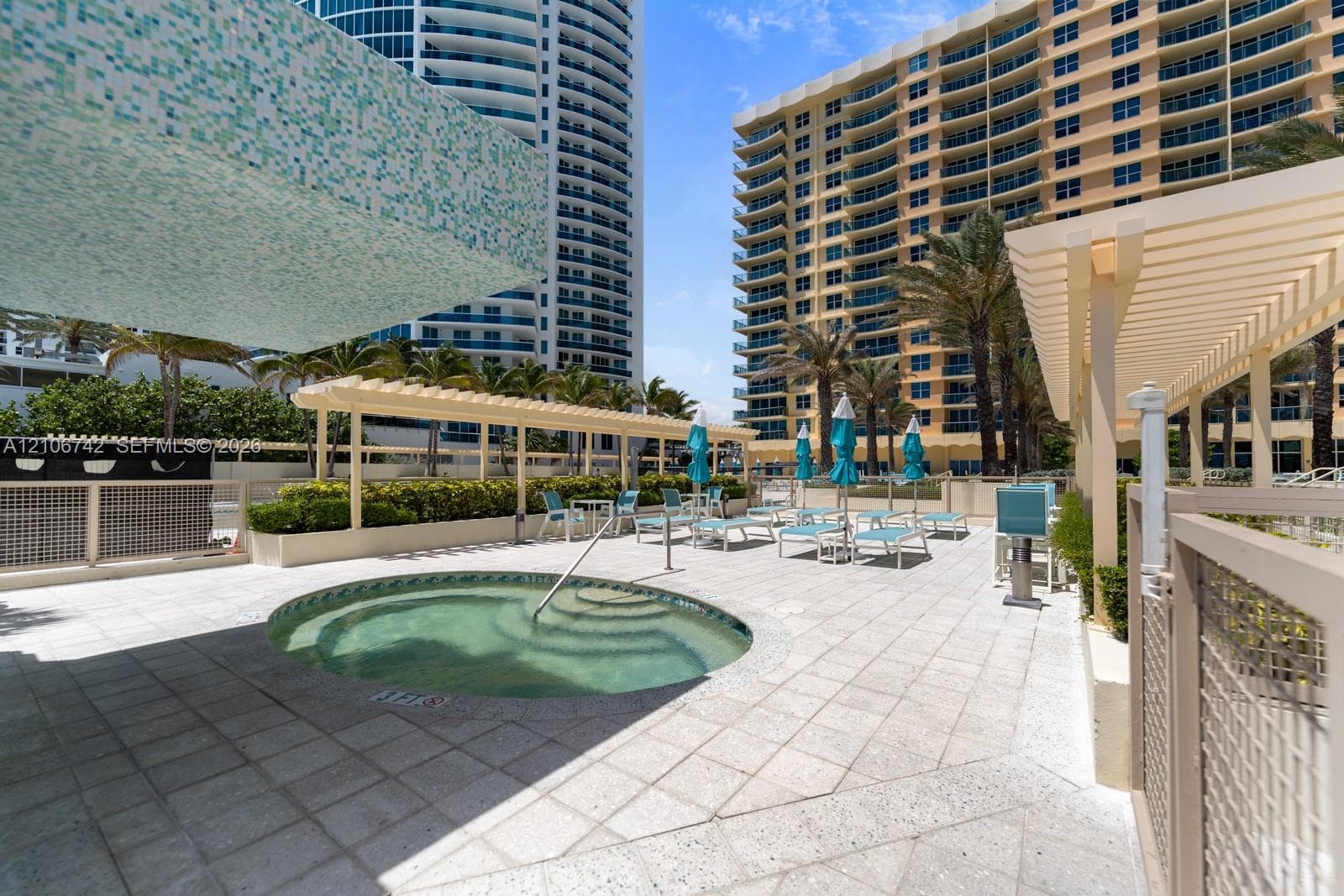 Circular spa with stone tile decking, wooden pergolas, and integrated landscaping