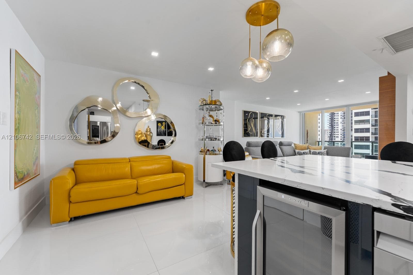 Kitchen island with stone-finish countertop and built-in under-counter refrigerator, large-format tile flooring, and multi-globe metallic pendant lighting
