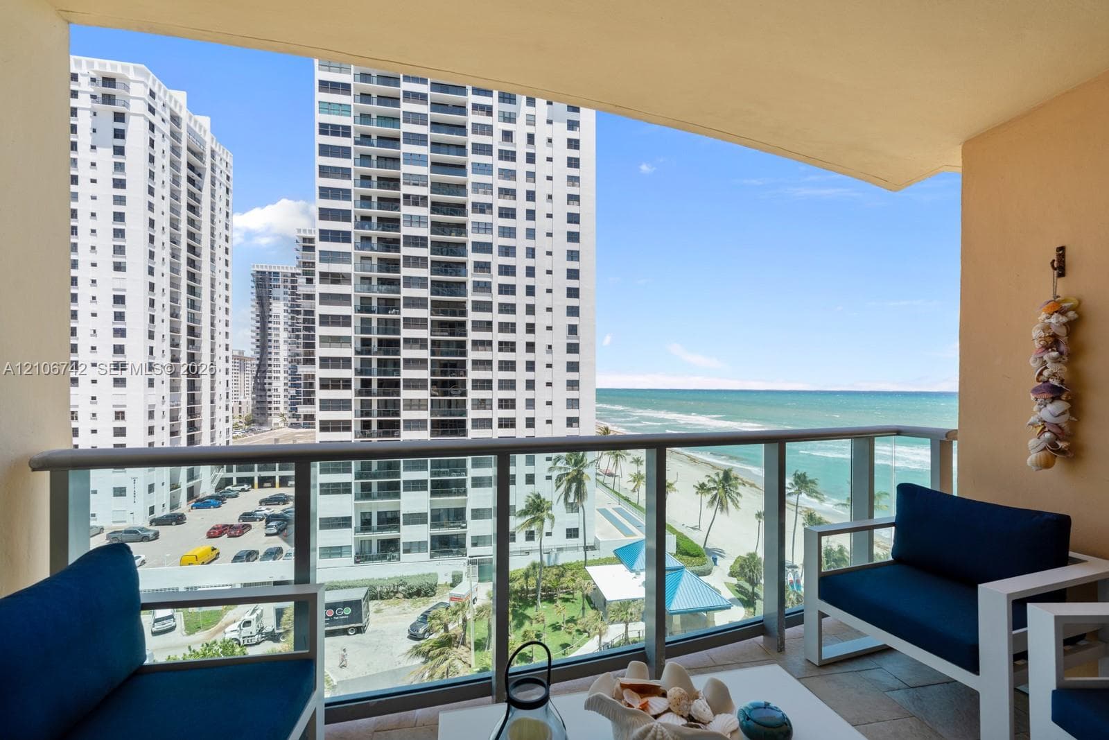 Private balcony featuring a glass-panel railing, neutral-tone tile flooring, and direct oceanfront scenery
