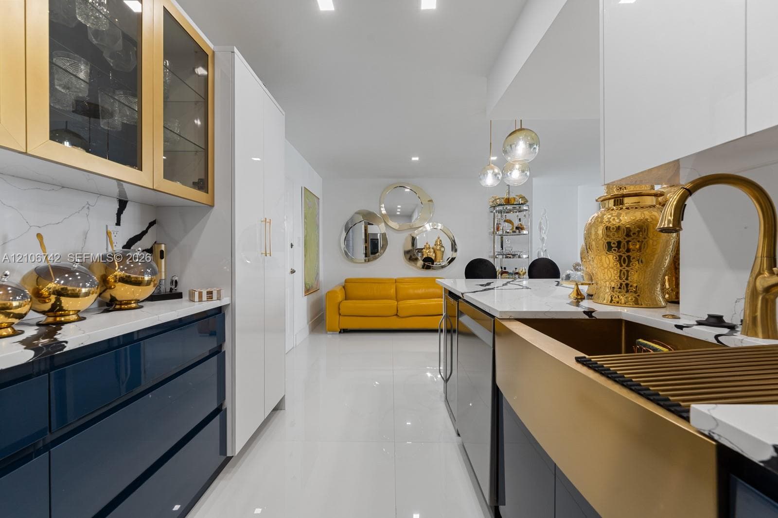 Custom kitchen featuring high-gloss cabinetry, stone-surface countertops, gold-toned farmhouse sink, and integrated gold-finish hardware