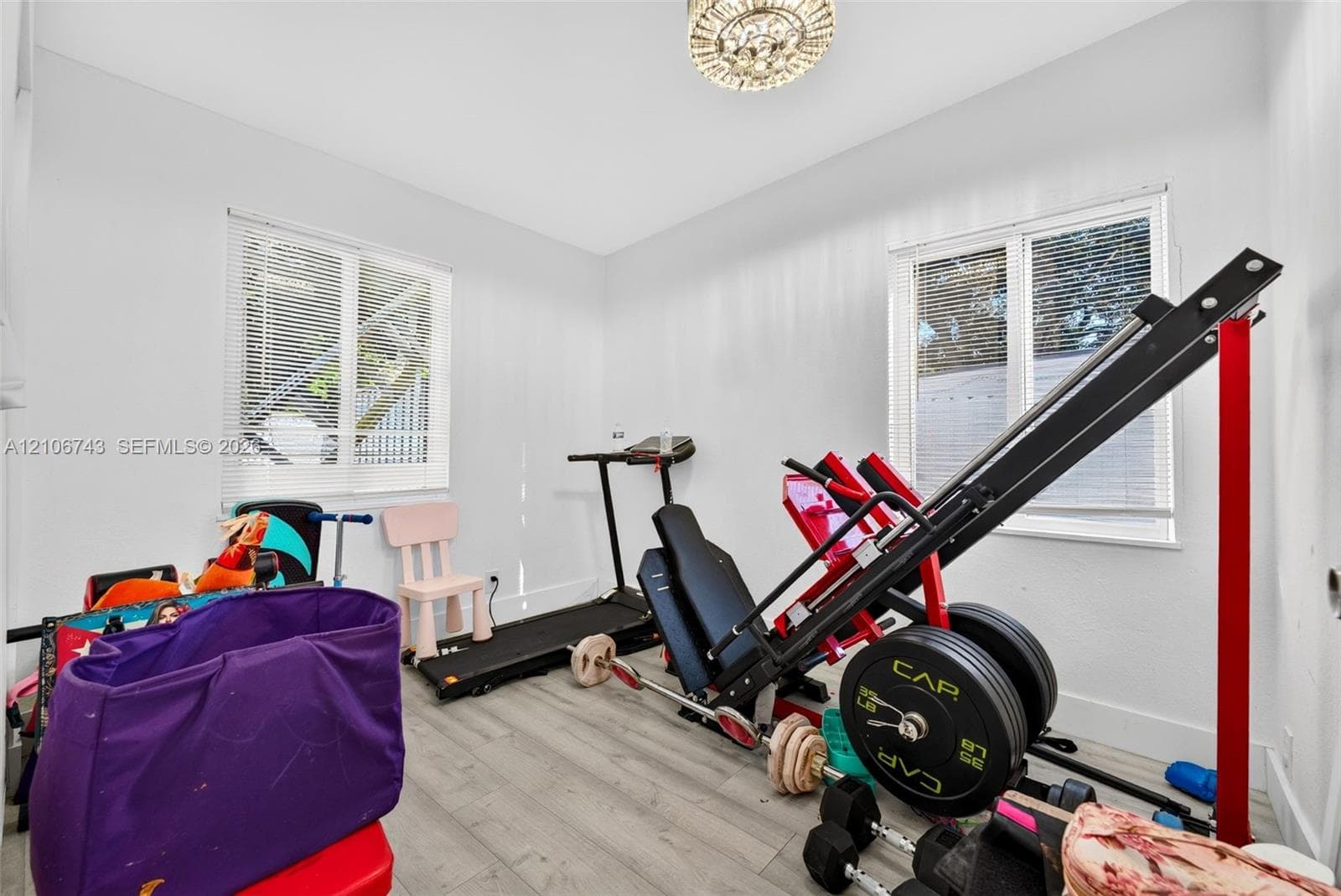 Room featuring wood-finish flooring, dual windows with integrated blinds, and a decorative flush-mount ceiling light fixture