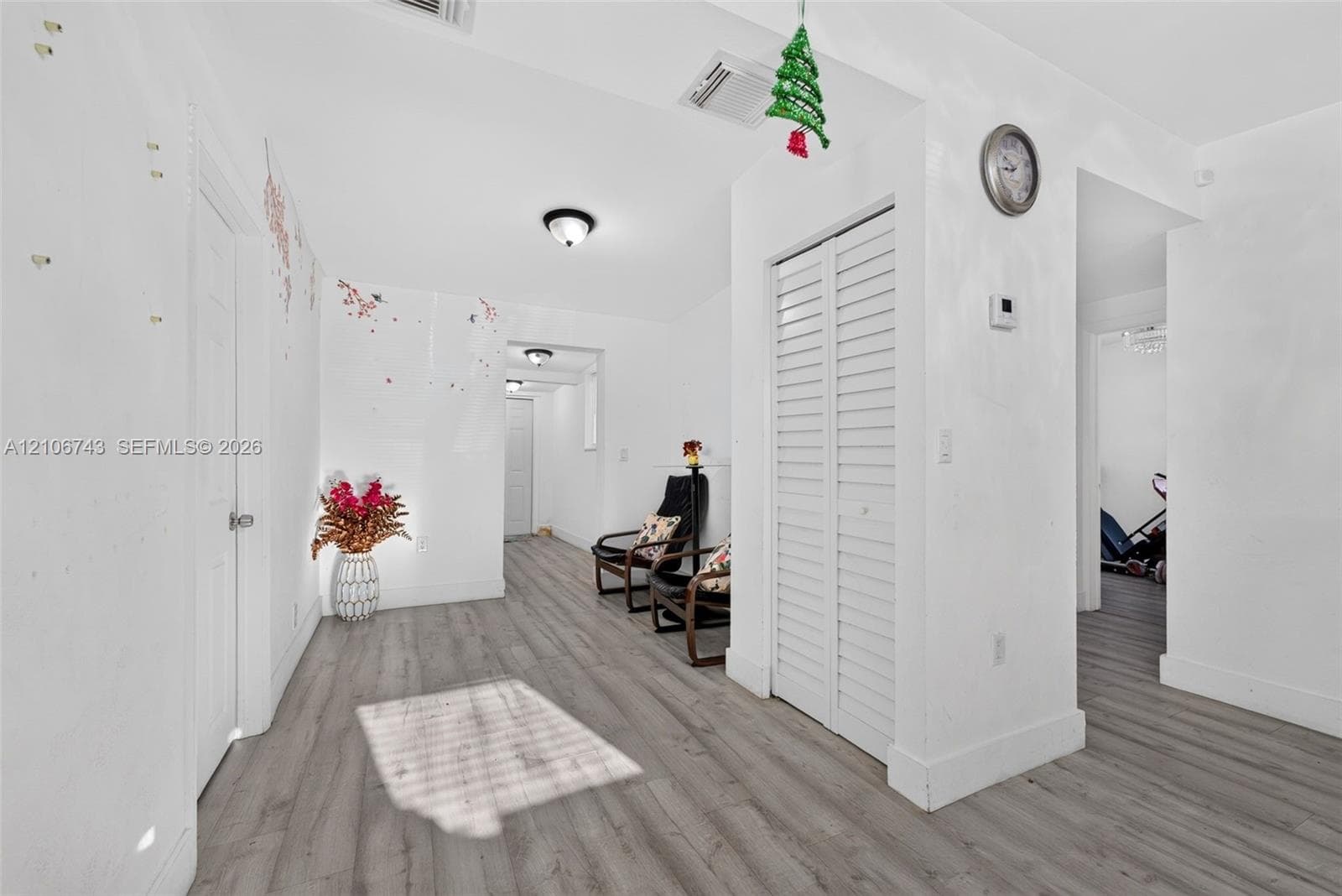 Wood-finish flooring, white paneled interior doors, and closet featuring white louvered doors
