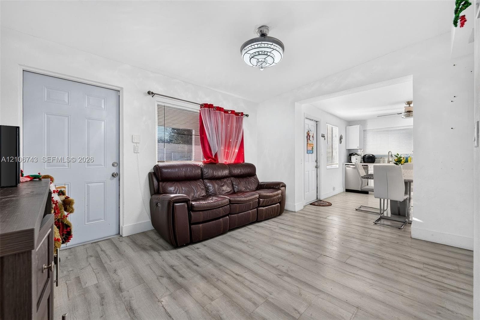 Neutral-toned living space featuring wood-finish flooring and a central flush-mount ceiling light fixture