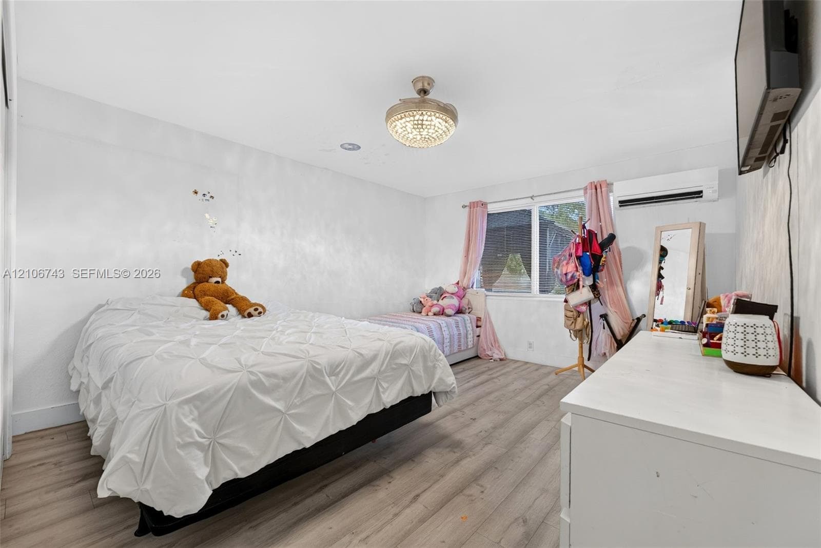 Room featuring wood-finish flooring, a wall-mounted ductless mini-split climate control unit, recessed lighting, and a crystal-accented ceiling light fixture