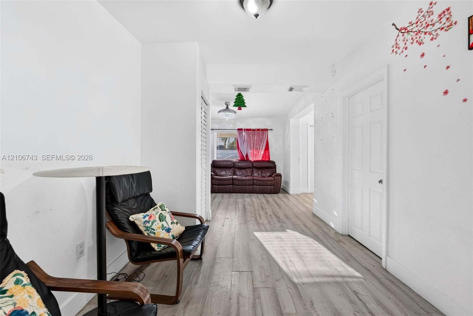 Interior space featuring wood-finish flooring, white walls, and a multi-panel door with brushed metal hardware