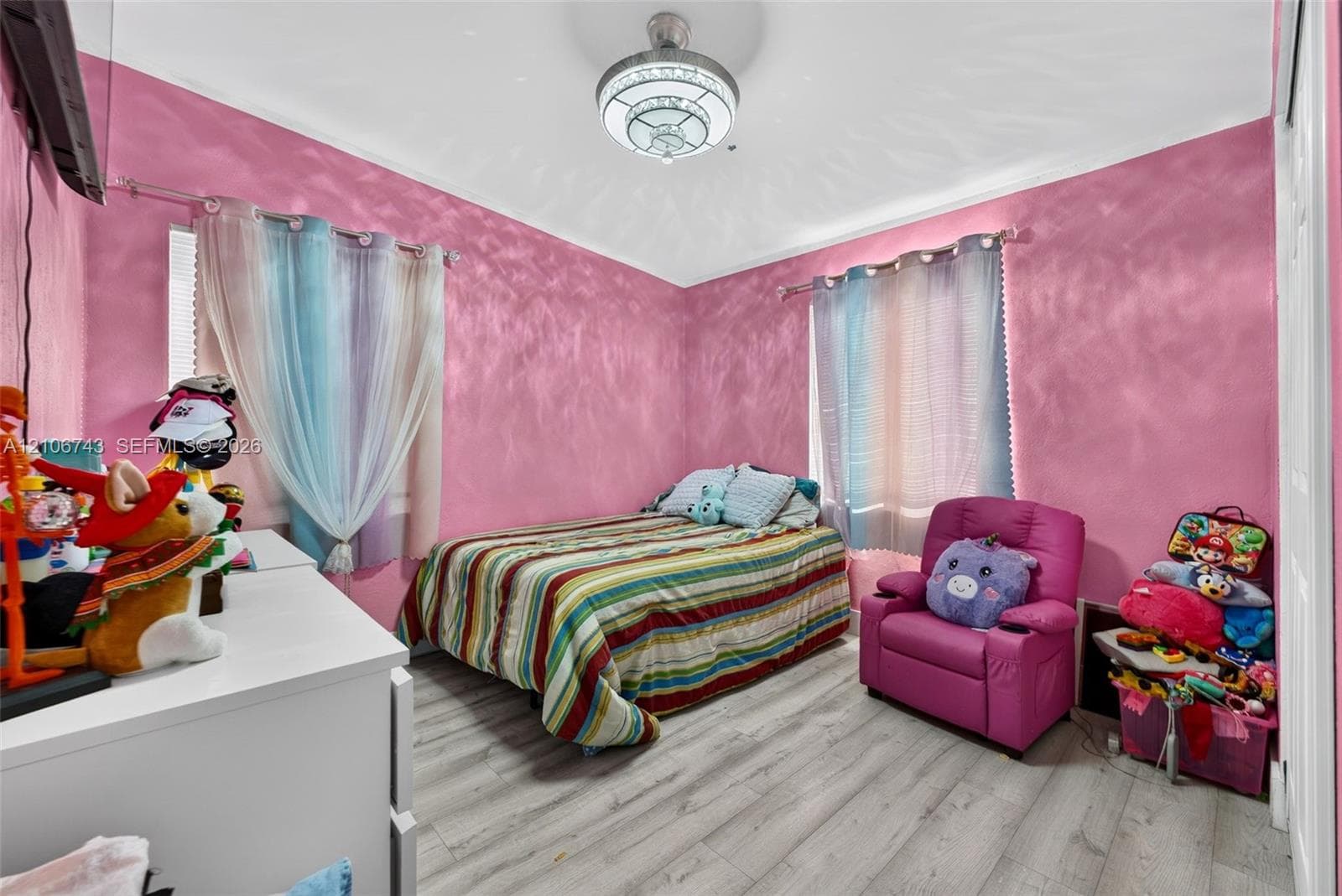 Room featuring light-toned wood-finish flooring and a central semi-flush mount light fixture with a metallic finish