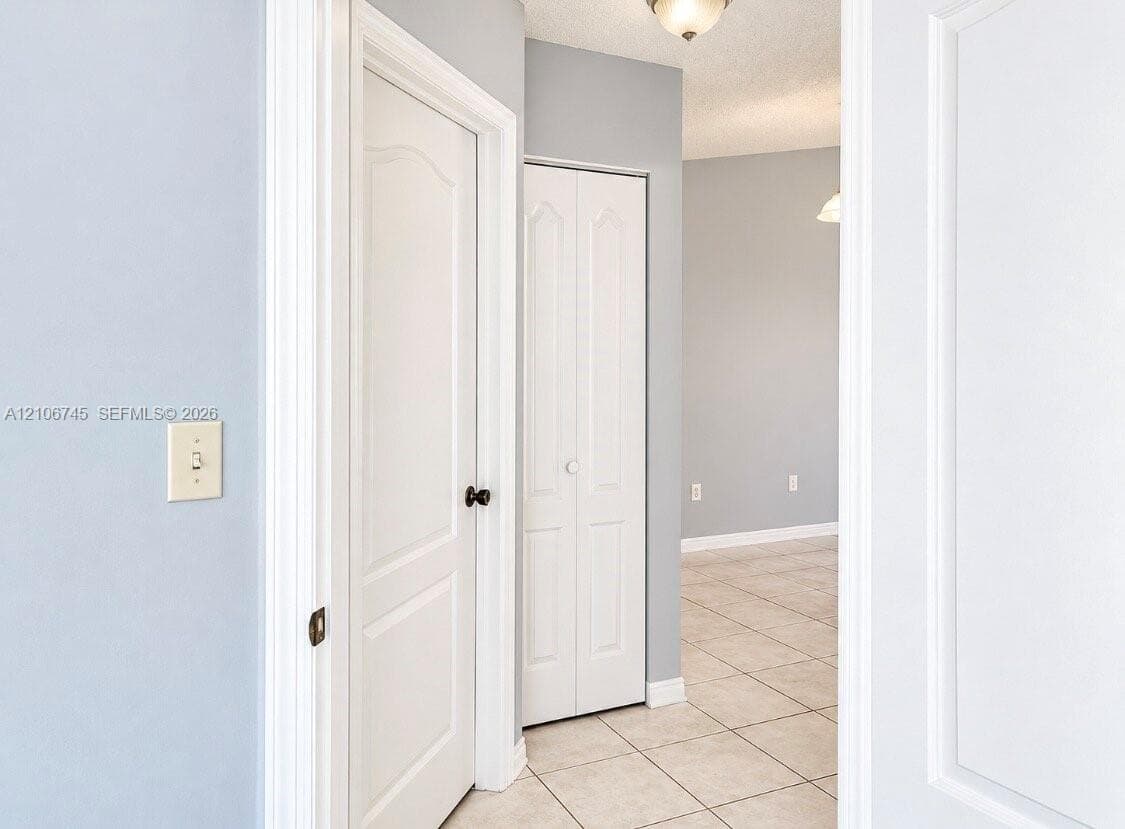 Neutral wall tones featuring white interior doors with arched-top panels, tile flooring, and bi-fold closet doors