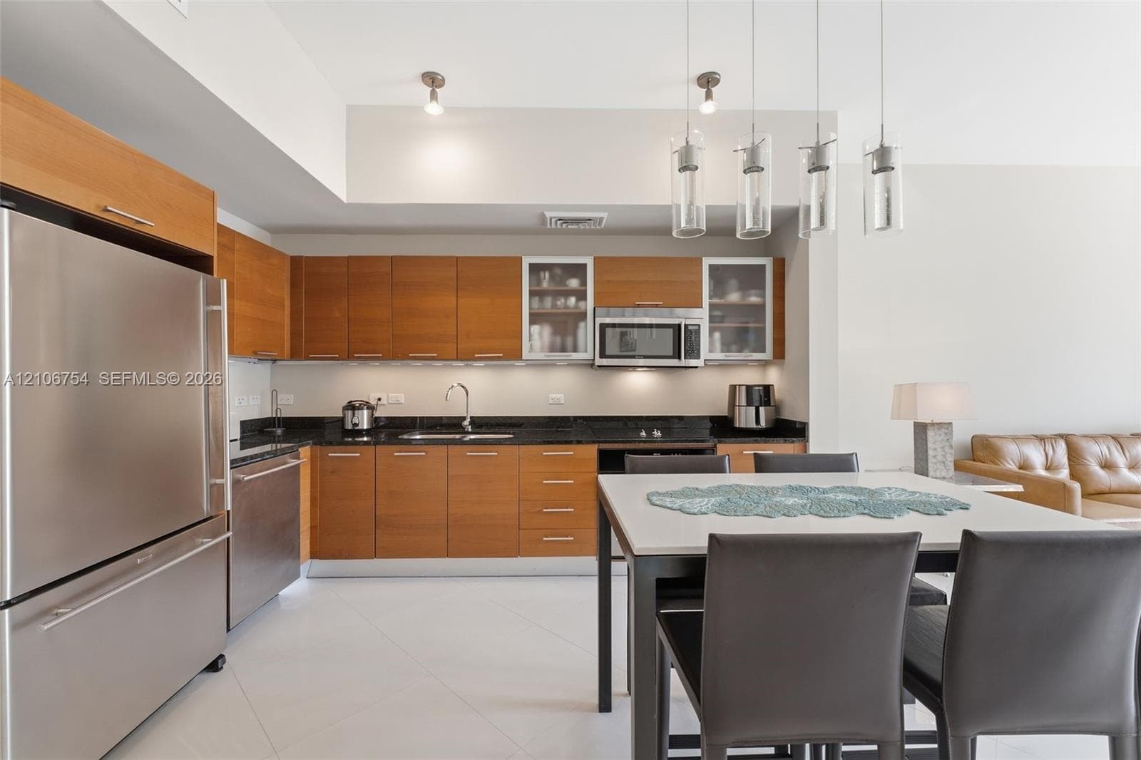 Kitchen featuring flat-panel wood cabinetry, dark stone countertops, stainless steel appliances, glass-front upper cabinet accents