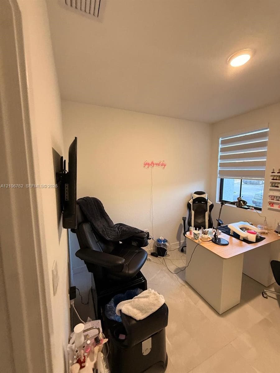 Room featuring neutral-toned walls, hard-surface flooring, and a window with horizontal blinds