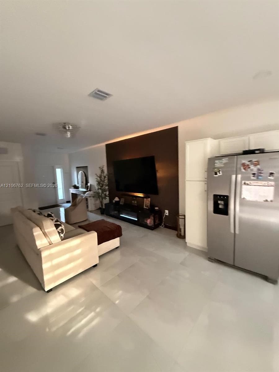 Large-format light-toned tile flooring, recessed ceiling lighting, and a distinct feature wall with integrated ambient lighting