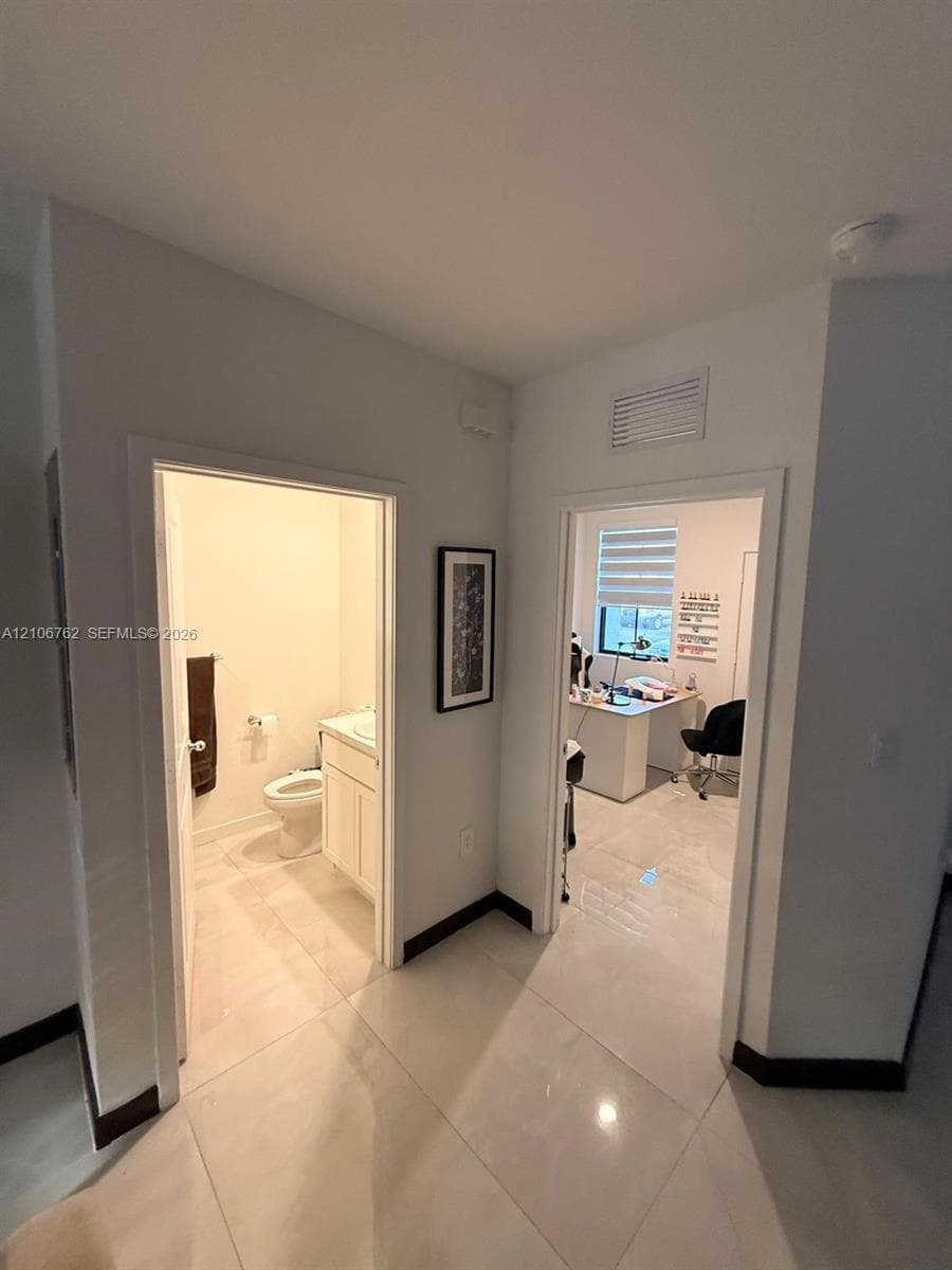 Interior hallway featuring polished large-format tile flooring and neutral wall tones