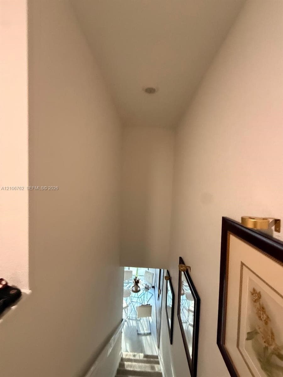 Stairwell featuring neutral wall finishes, carpeted steps, and brass-finish wall-mounted light fixtures