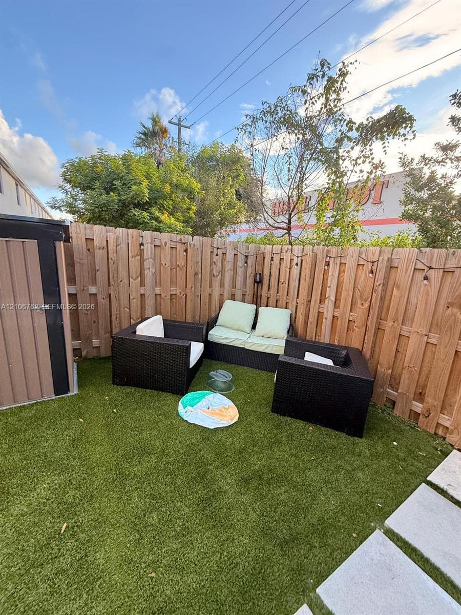 Private backyard featuring vertical wood fencing, synthetic turf, and a structural storage shed