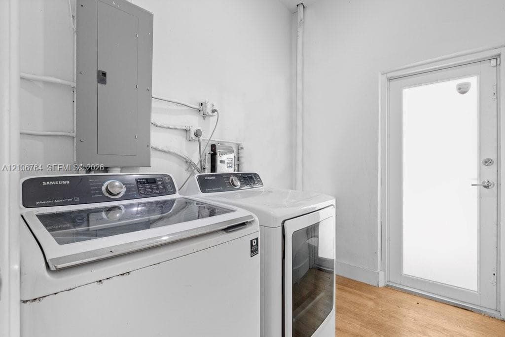 Laundry area featuring wood-finish flooring and a white exterior door with glass paneling