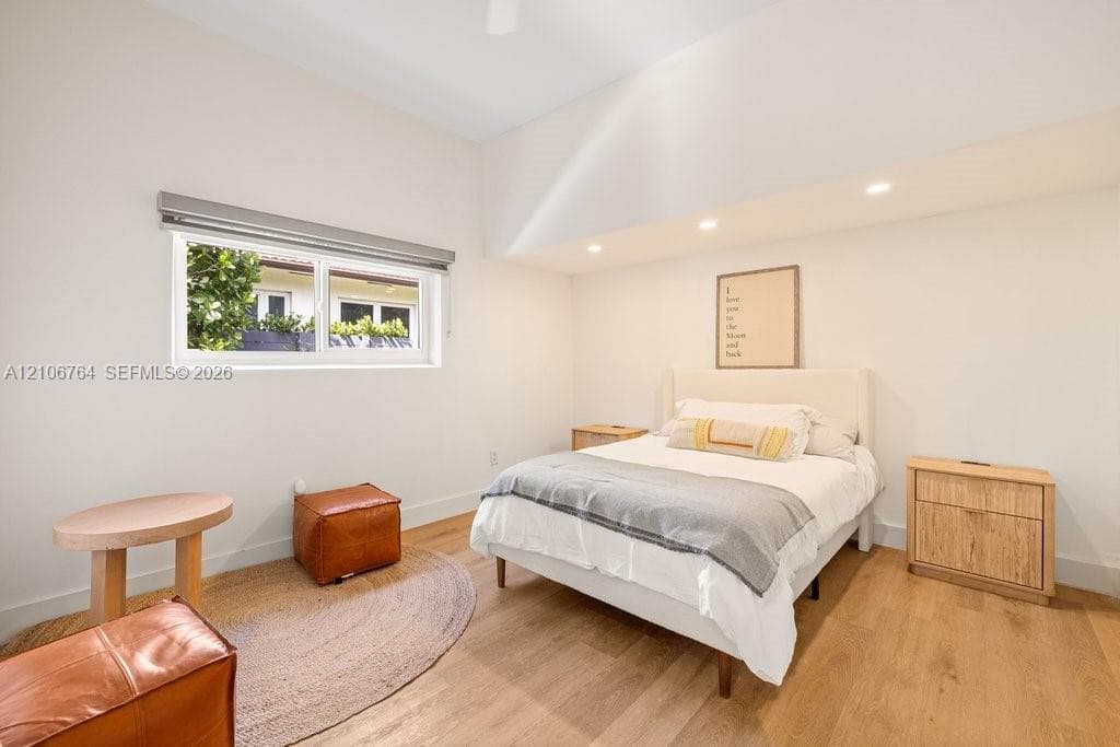 High-ceiling room featuring recessed lighting, wood-finish flooring, and a window with a roller shade