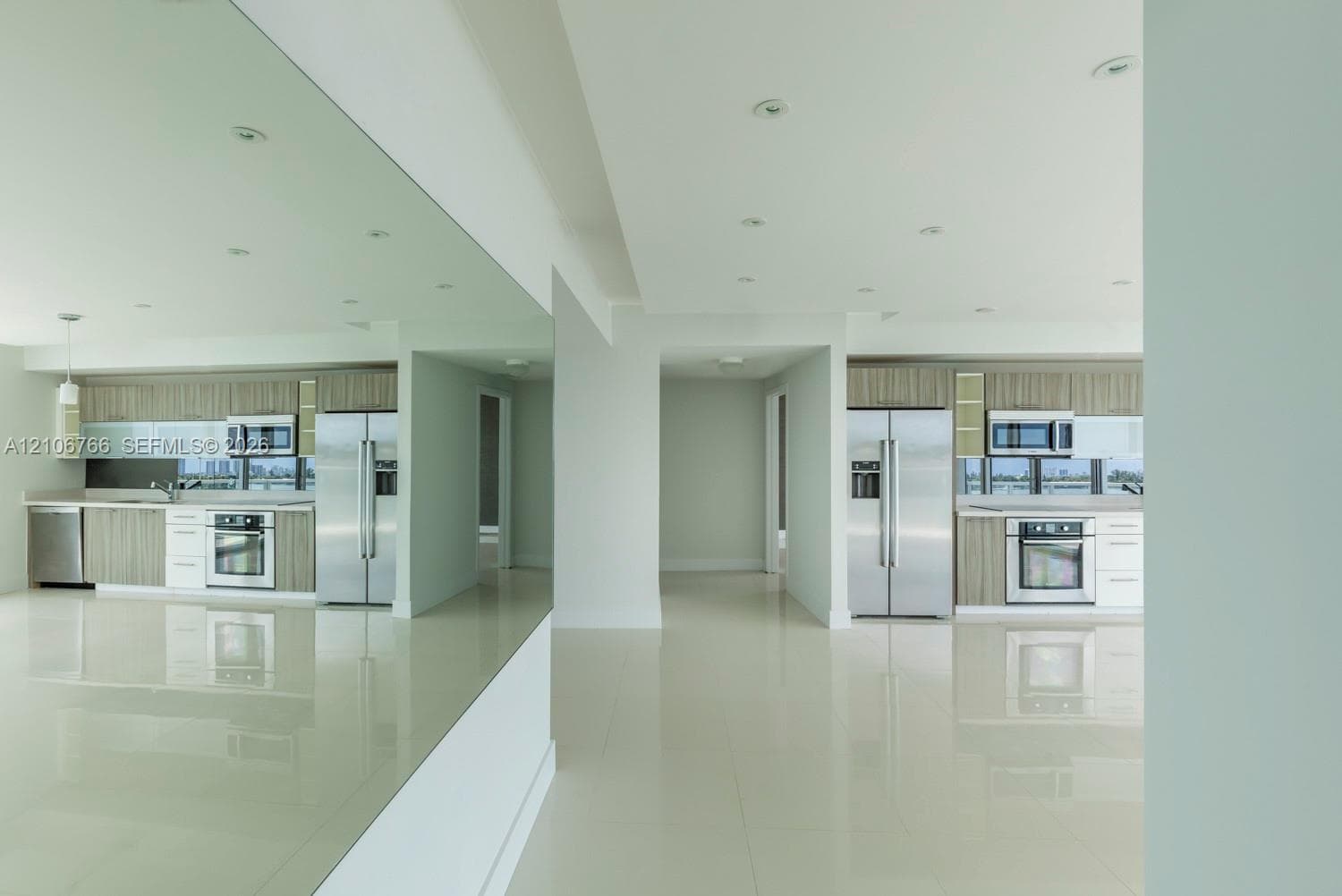 Kitchen featuring flat-panel cabinetry, stainless steel appliances, polished flooring, recessed lighting, and a full-height wall mirror