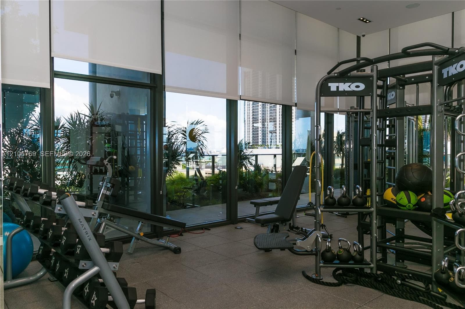 Floor-to-ceiling glass windows with retractable roller shades, large-format tile flooring, and recessed ceiling lighting