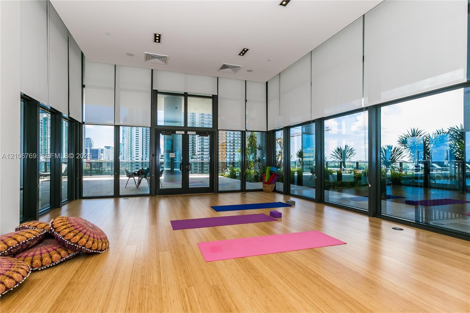 Open-concept room featuring floor-to-ceiling glass walls, wood-finish flooring, recessed lighting, and automated solar shades