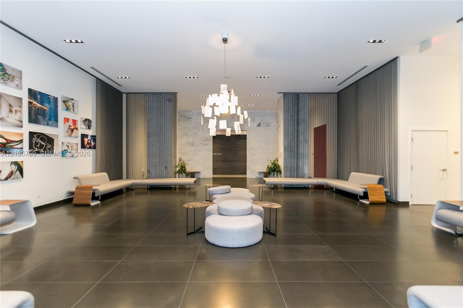 Large-format tile flooring, stone wall cladding, floor-to-ceiling drapery, and a contemporary architectural pendant light fixture