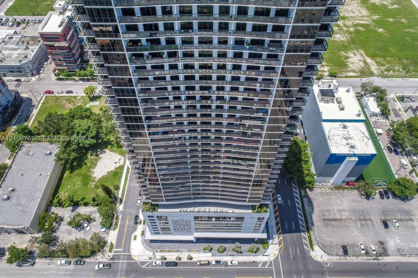 High-rise residential tower featuring a glass-facade exterior, tiered structural design, and perimeter balconies spanning the building elevation