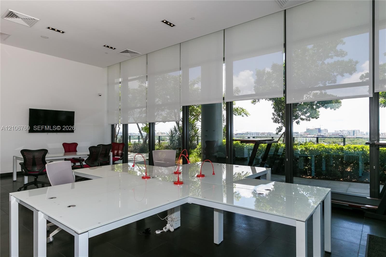 Floor-to-ceiling windows with integrated roller shades, dark tile flooring, recessed ceiling lighting, and a private terrace with a metal railing