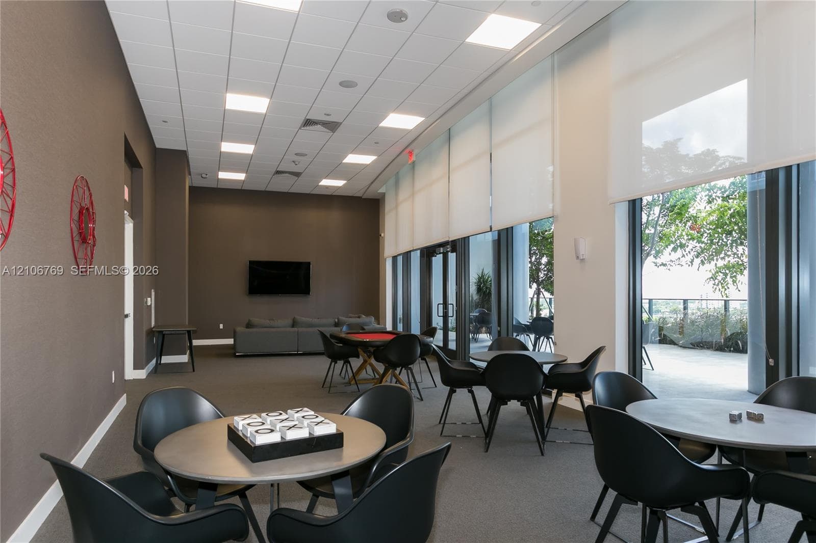 Expansive interior space featuring high ceilings with recessed lighting, floor-to-ceiling windows, motorized roller shades, and direct access to an outdoor patio